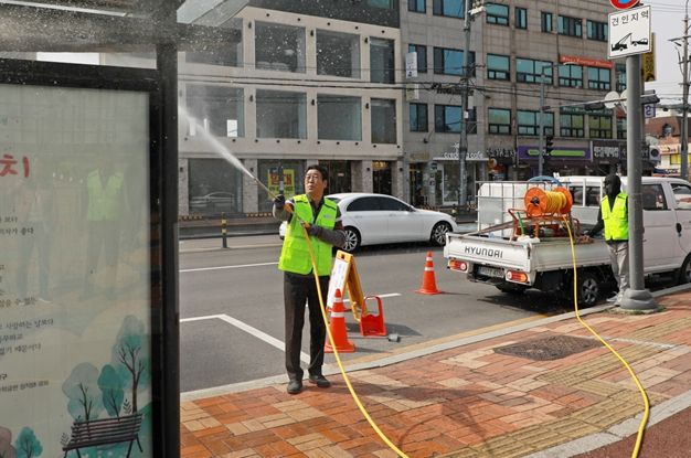김기배 팔달구청장이 구청사 앞 버스정류장 세척에 동참하고 있다.
